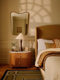 a bed room with a neatly made bed and a mirror on the wall above it