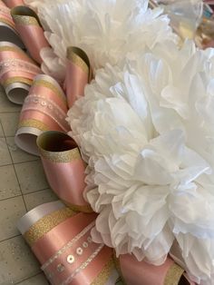 several rolls of pink and gold ribbon with white flowers on them sitting next to each other