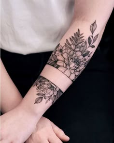 a woman's arm with flowers and leaves on it