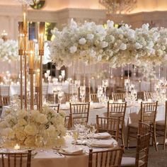 an elegant wedding setup with tall centerpieces and white flowers on the top tables