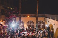 a large group of people standing around in front of a building with lights on it