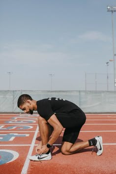 a man tying his shoes on the running track