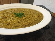 a white bowl filled with green food on top of a black counter next to a door