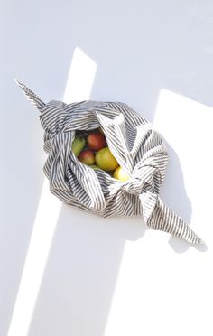 a striped bag with apples in it sitting on the floor next to a white wall