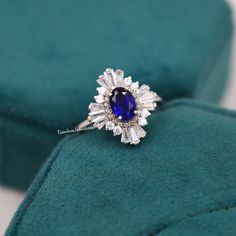 a diamond and blue sapphire ring sitting on top of a velvet cushion in a box