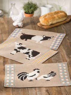 three placemats with farm animals on them sitting on top of a wooden table