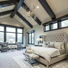 a large bedroom with high ceilings and lots of windows on the wall, along with an upholstered bed