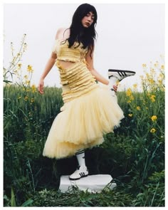 a woman in a yellow dress holding a tennis racquet on top of a white pedestal