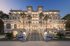 a large white building with palm trees and lights on it's front steps at night