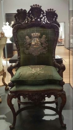 an ornate chair with green cushions on display