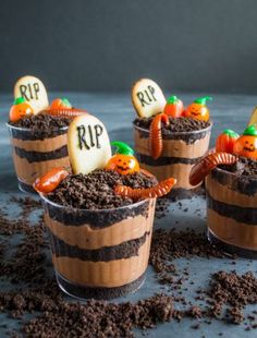 three halloween desserts in plastic cups with dirt on the ground