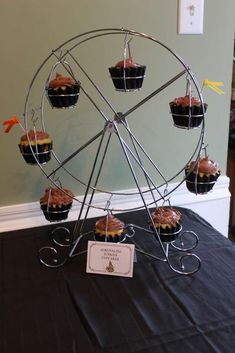 a ferris wheel with cupcakes in it sitting on a black tablecloth covered table