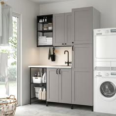 a washer, dryer and cabinets in a room with a door open to the outside