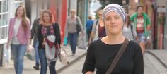 a woman with a bandana on walking down the street in front of other people