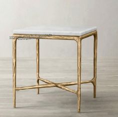 a white marble topped end table with gold metal frame and wood legs, against a gray wall