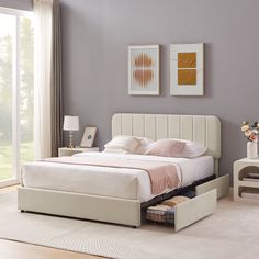 a white bed sitting in a bedroom next to a table with drawers on it and a window