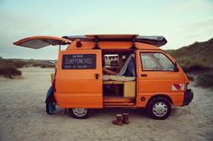 an orange van parked on top of a sandy beach