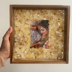 a person holding up a wooden frame with an image of a man and woman in it