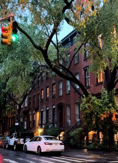 cars are parked on the street in front of some trees and buildings at night time