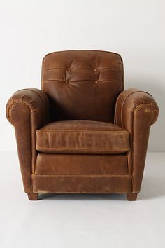 a brown leather chair sitting on top of a white floor