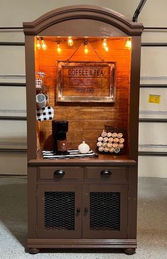 the coffee and tea stand is made out of an old cabinet with lights on it