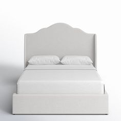 a white bed with two pillows on top of it