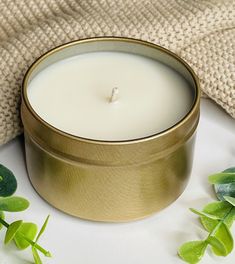 a candle sitting on top of a table next to green leaves