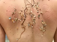 the back of a woman's body is covered in sea shells and other things