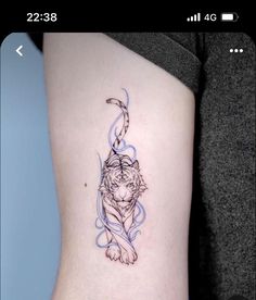 a small tiger tattoo on the side of a woman's leg, with blue ink