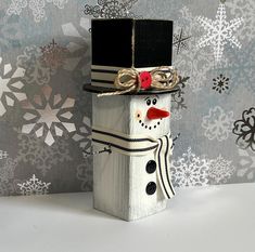 a wooden block with a snowman wearing a hat and scarf on it's head