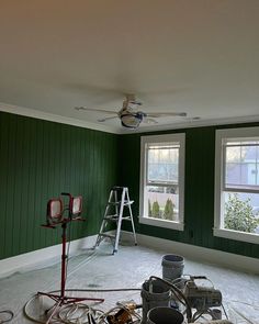 an empty room with green walls and white paint on the floor, tools are scattered around