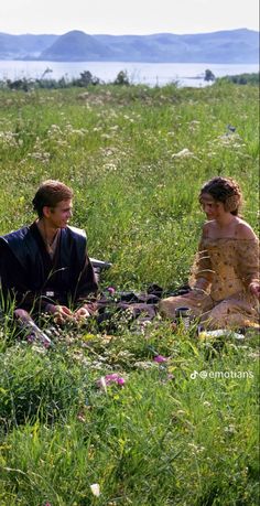 two people are sitting in the grass talking