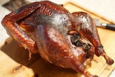 a whole chicken sitting on top of a cutting board with a knife next to it