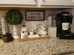 a kitchen counter with coffee cups, mugs and other items sitting on top of it