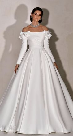 a woman in a white wedding dress with long sleeves and an off the shoulder neckline