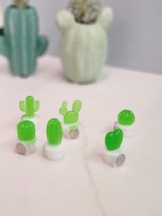 green and white plastic cactus planters sitting on a table next to a potted cacti