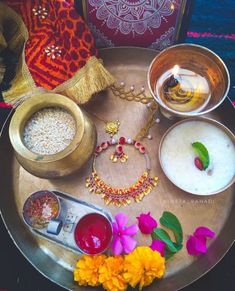 an assortment of jewelry on a tray with flowers and other items in bowls next to it