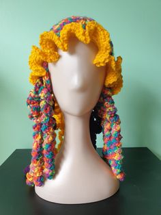 a white mannequin head with multicolored crocheted hair on it