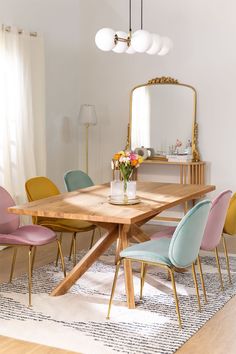 a dining room table with colorful chairs and a large mirror on the wall above it