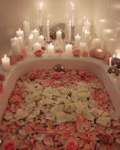 a bathtub filled with lots of flowers and candles