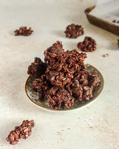 a glass bowl filled with granola on top of a white counter next to a cookie sheet