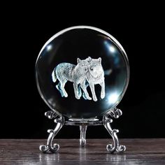 an image of two animals in a glass ball on top of a wooden table with black background