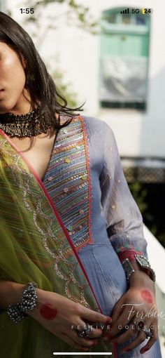 a woman in a blue sari with jewelry on her neck and hands behind her back