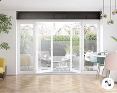 an open living room with sliding glass doors and chairs in the corner, next to a potted plant