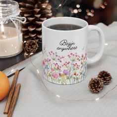 a cup of coffee sitting on top of a table next to an orange and some cinnamons