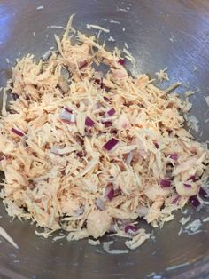 a metal bowl filled with shredded chicken and red onion pieces on top of it's side