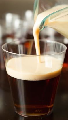 a person pouring liquid into a glass on top of a table