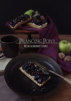 a piece of pie on a black plate with a fork and coffee cup in the background