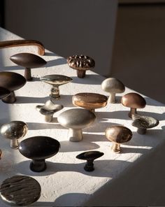 an assortment of knobs and handles on a white surface with sunlight coming through the window