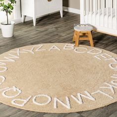 a round rug with words written in white on the floor next to a crib